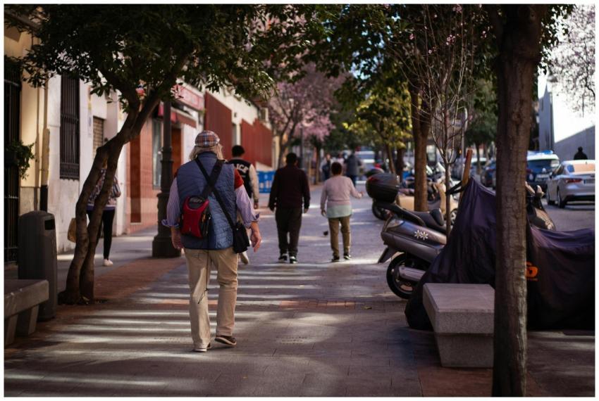 A city sidewalk with pedestrians walking under the