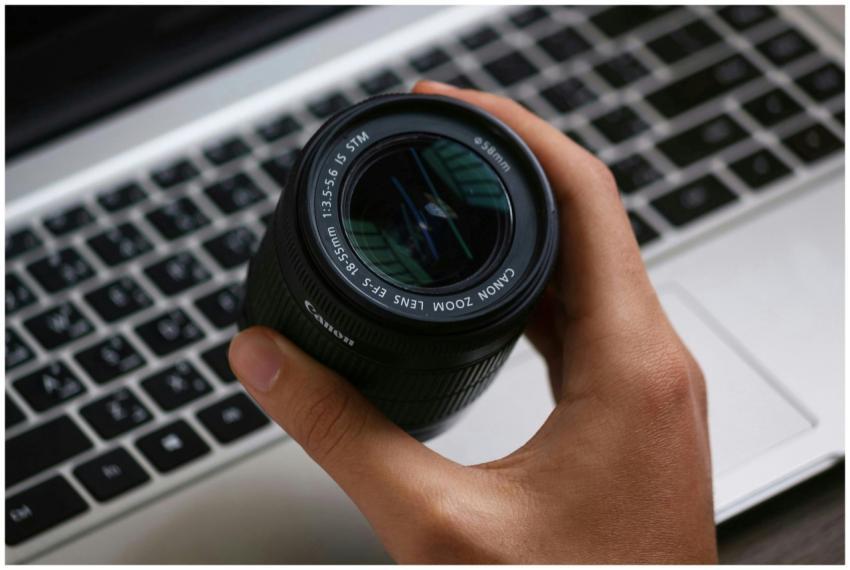 a person holding black canon lens