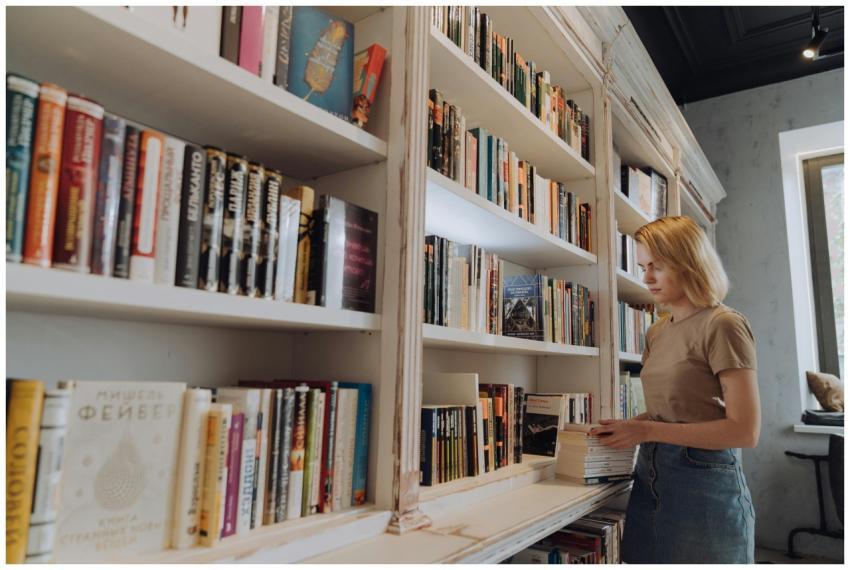 A woman organizing books on a bookshelf in a libra