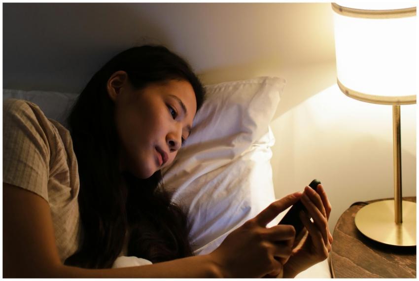A woman lying in bed at night using a smartphone,