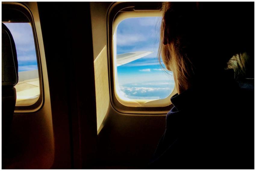 Silhouette of a woman looking out an airplane wind