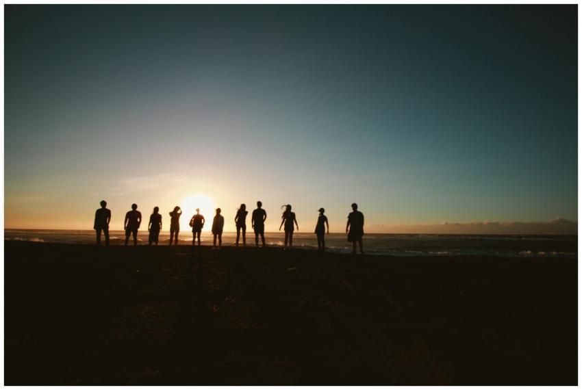 A group of friends standing on a beach, silhouette
