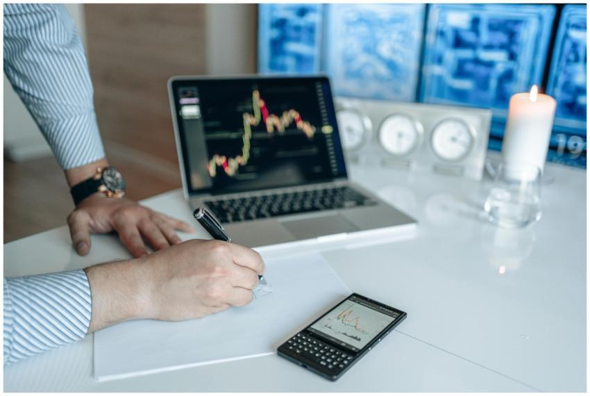 Man analyzing stock market trends on a laptop, wri