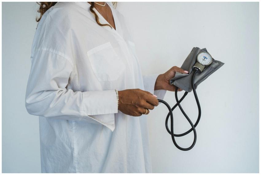 A healthcare professional in white holding a sphyg