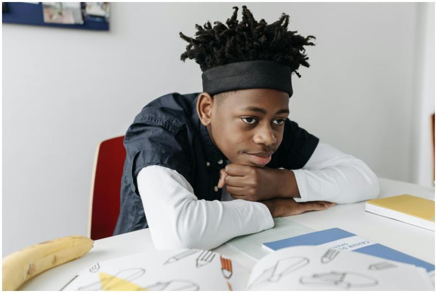 A young student with dreadlocks sitting at a desk
