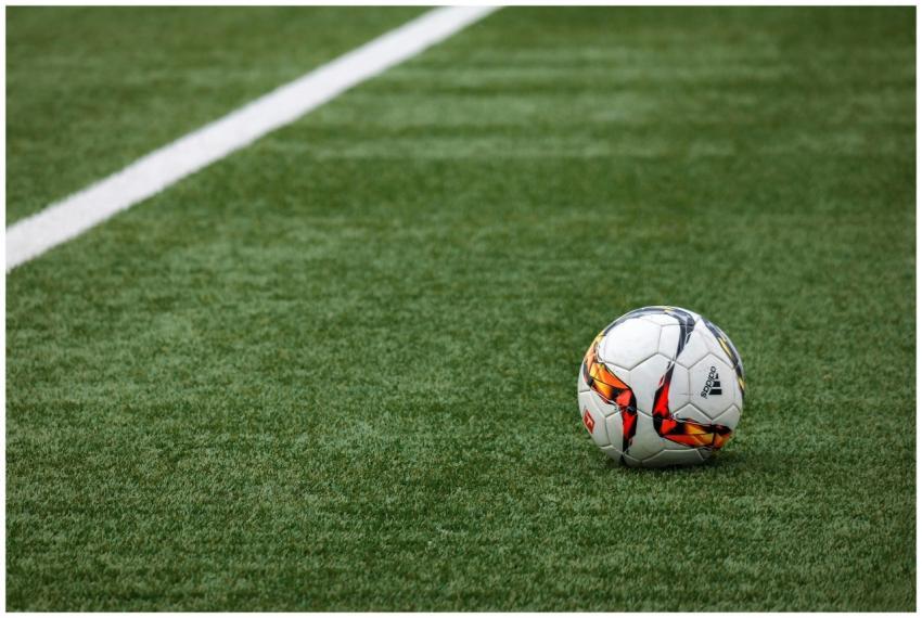 A vibrant soccer ball resting on a pristine grass