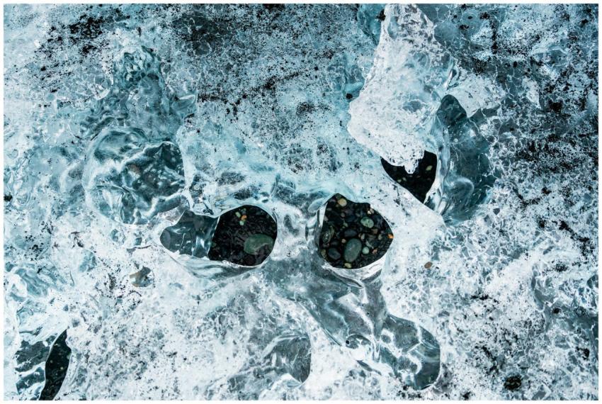 Close-up of ice with embedded rocks, showcasing wi