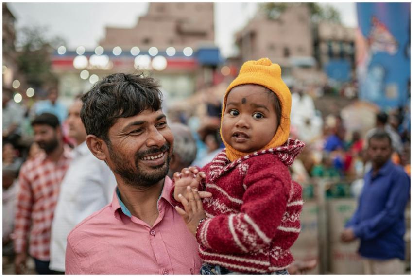 A father holds his child outdoors in the bustling