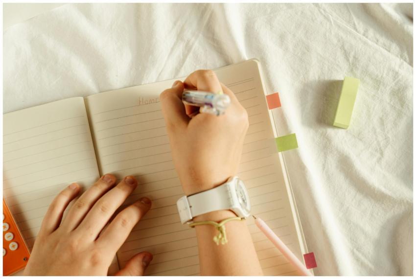 A close-up view of hands writing notes in a notebo