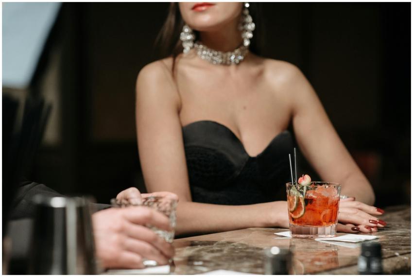 A woman in an elegant dress enjoys a cocktail at a