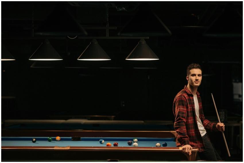 A man leaning on a billiard table holding a cue st