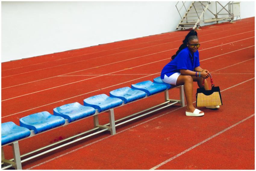 Woman sitting on blue bench in sports track area h