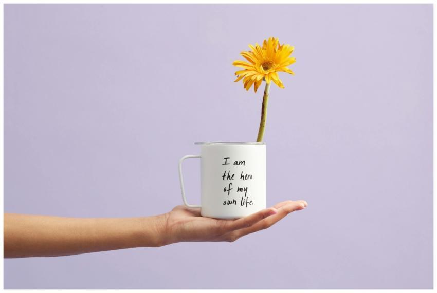 Hand holding a mug with a sunflower and motivation