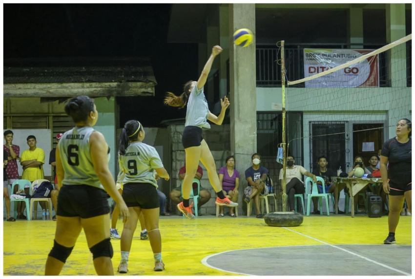 A competitive indoor volleyball game with women at
