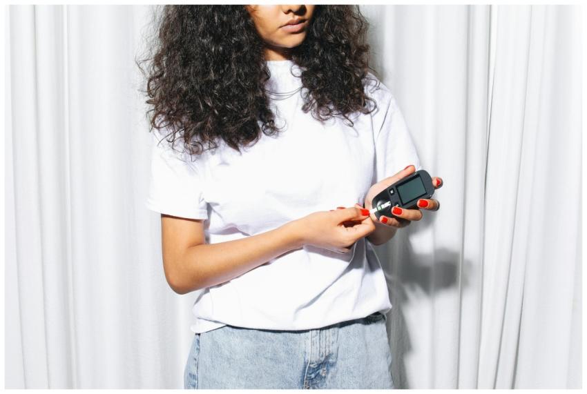 A woman using a glucometer to check blood sugar le