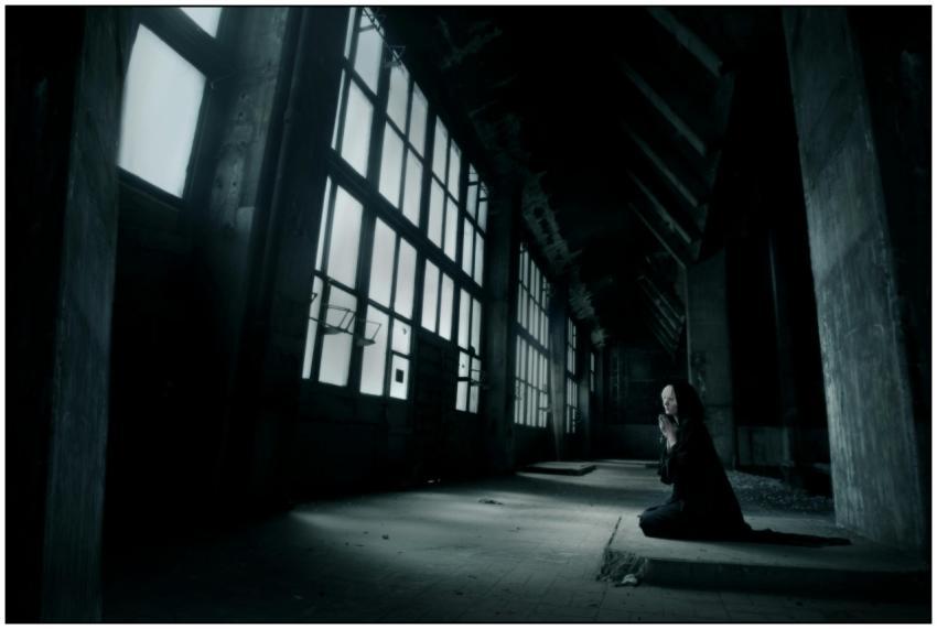 A haunting scene with a lone figure kneeling and p