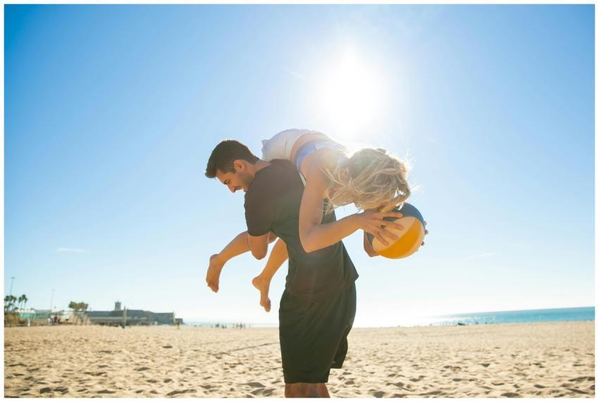 A carefree couple playing with a volleyball on a s