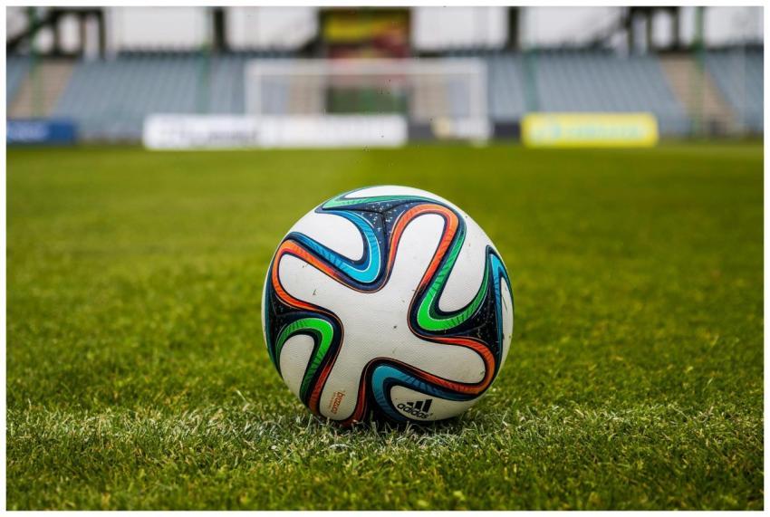 A vibrant adidas soccer ball on a green field, per