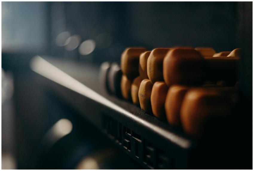 A rack of dumbbells in a dimly lit gym, highlighti