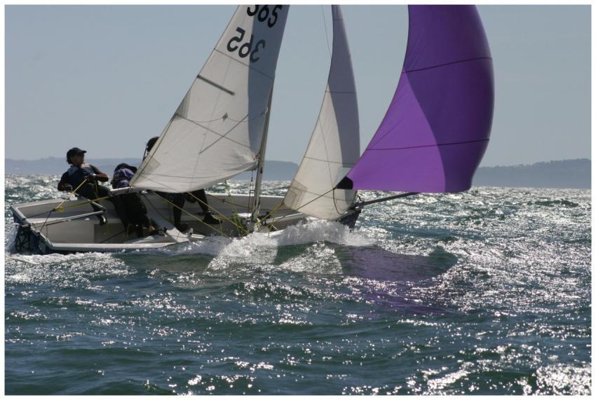 Two sailors navigate a sailboat with colorful spin