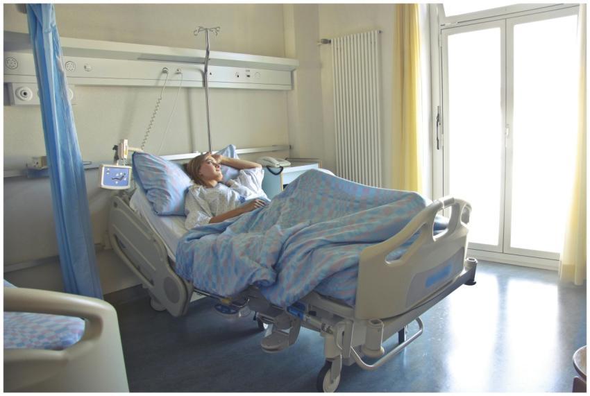 A woman lying in a hospital bed in a bright, softl