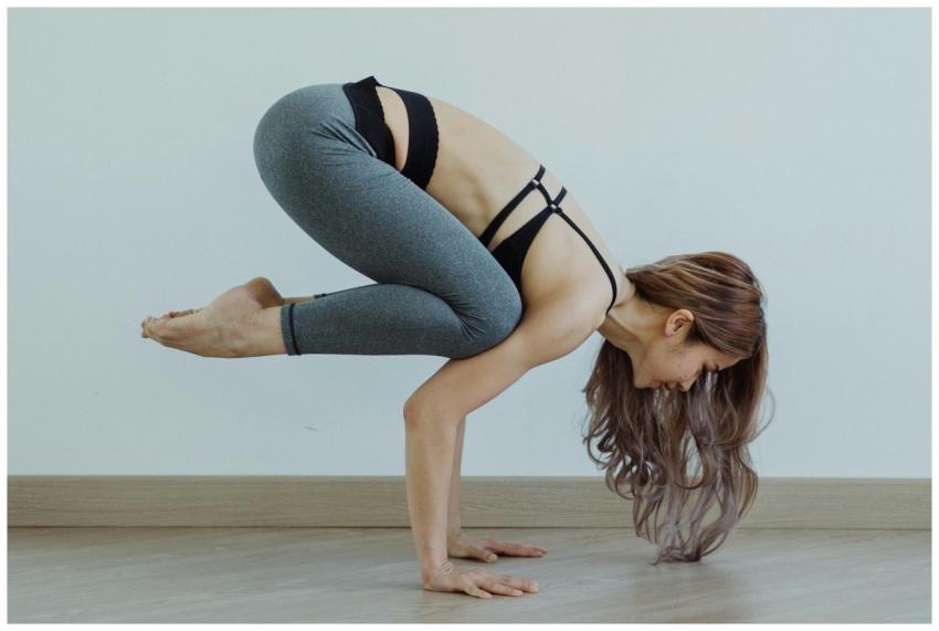 A woman holds a challenging yoga pose indoors, dem