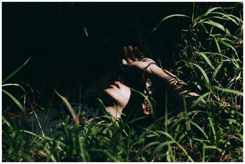 A person partially concealed under tall grass, cre