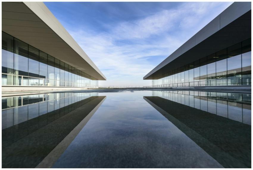 Futuristic glass building mirrored on a still wate