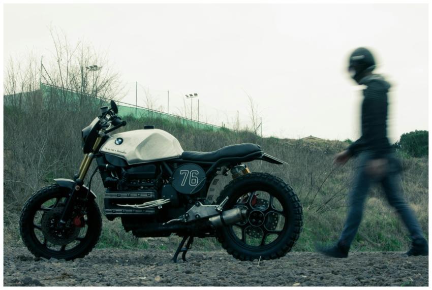 Blurry man walking past BMW motorcycle outdoors, s