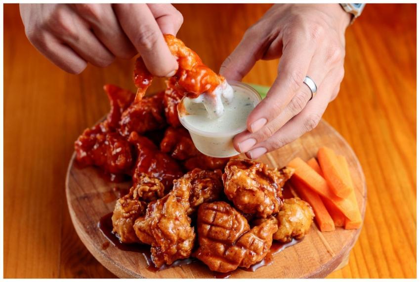 Delicious chicken wings on a wooden platter with d