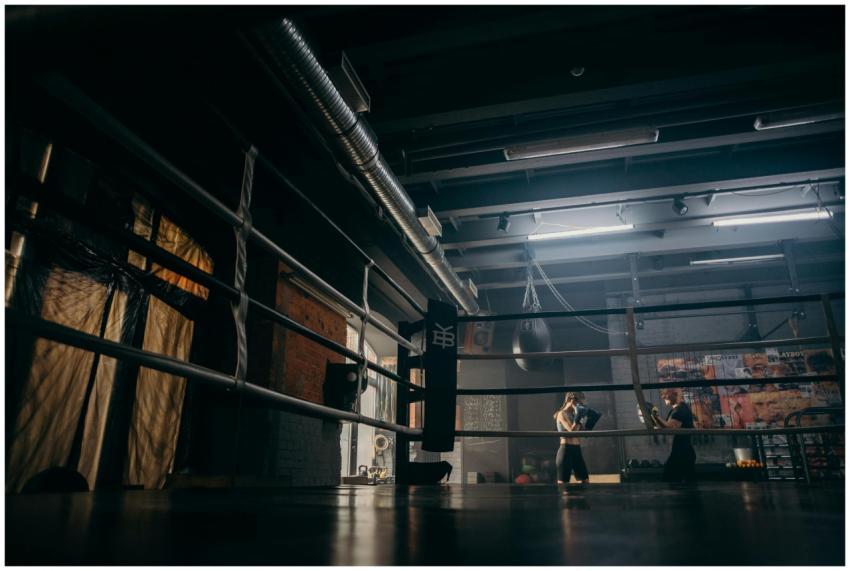 Two boxers sparring in a dimly lit gym, practicing