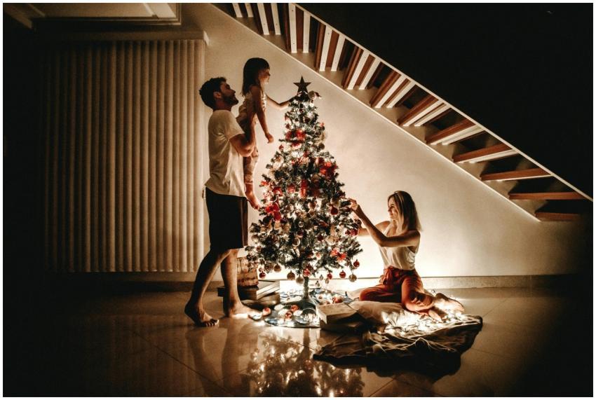 A family decorates a Christmas tree, bringing warm