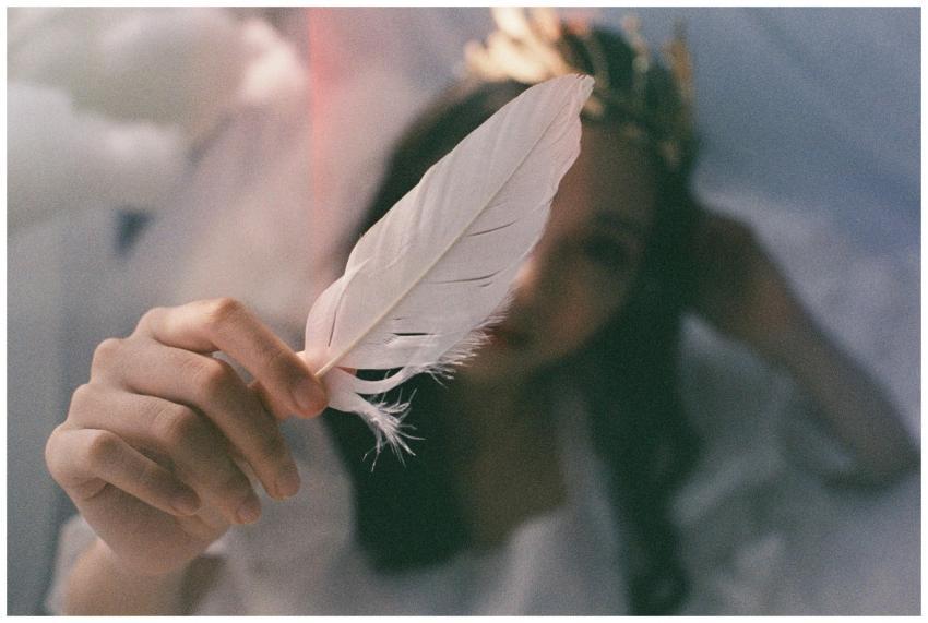 A woman holds a delicate white feather, adding an