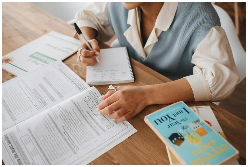 A person studying at a desk with books and a notep