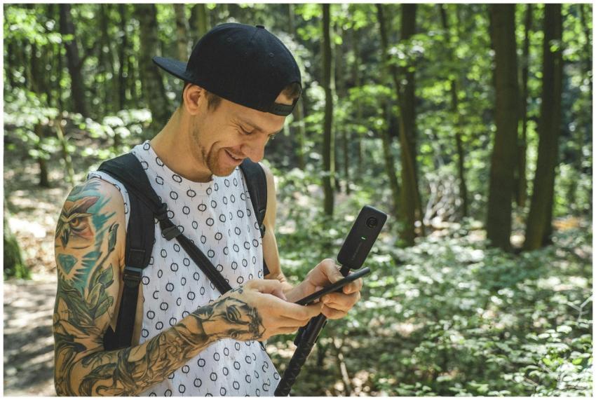 A person using a camera in a sunlit forest in Berl