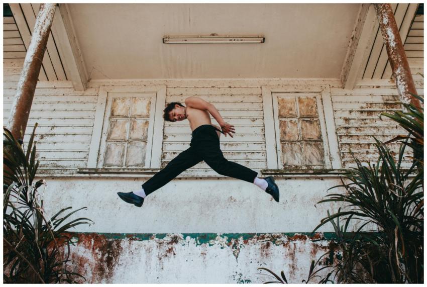 Man gracefully jumps mid-air in front of an aged w