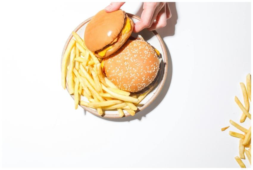 A top view of two cheeseburgers and fries on a pla