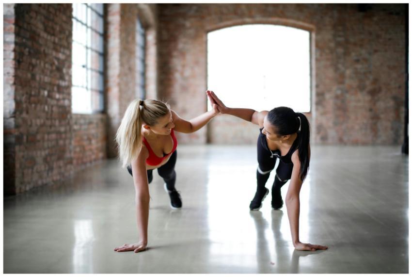 Fit smiling women in sportswear looking at each ot