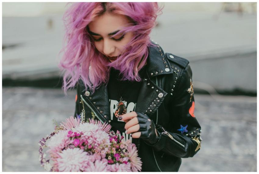 A stylish young woman with purple hair holding a b