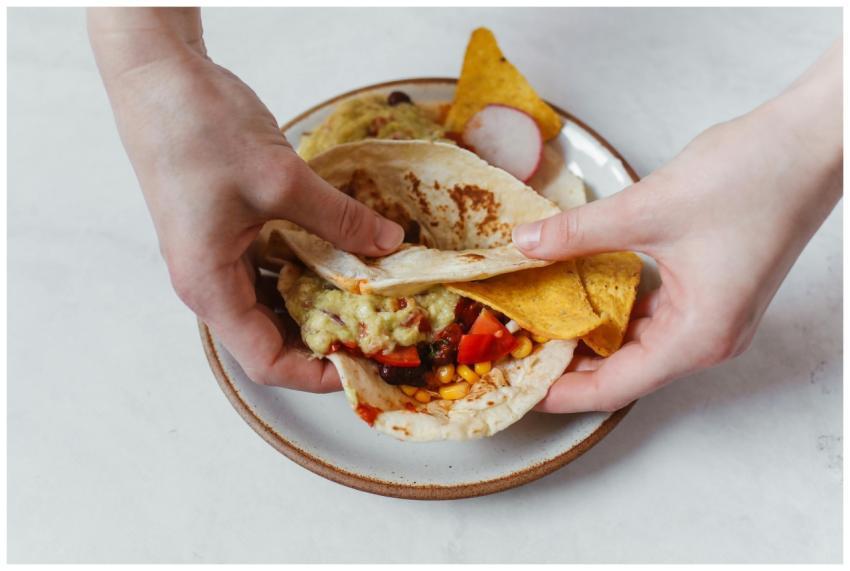 Close-up of hands holding a Mexican taco with nach