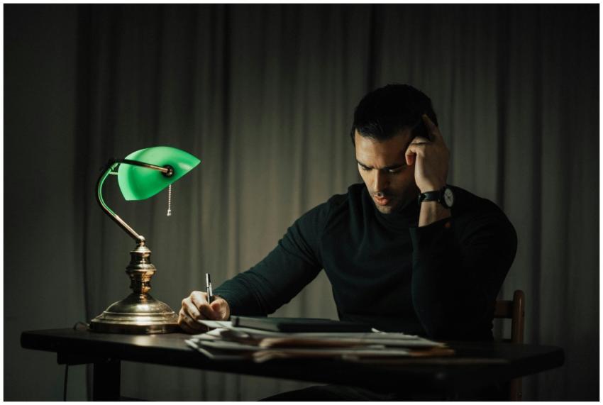 Focused man working late at a desk, lit by a chara