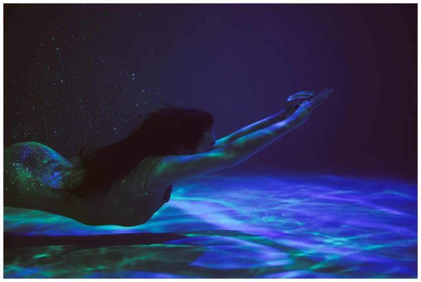 A serene woman swimming underwater, surrounded by