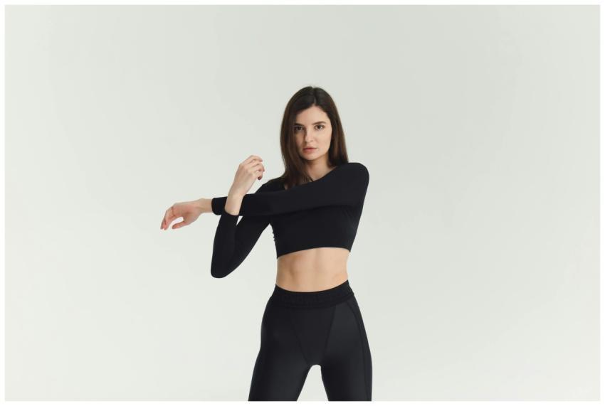 Woman in black activewear stretching indoors, show