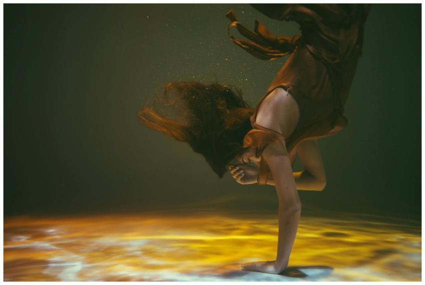 A woman gracefully poses underwater, enveloped in