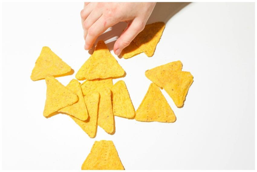 A close-up of a hand grabbing crispy triangular to