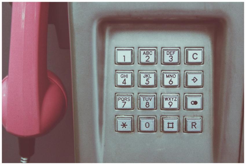 Close-up of a vintage payphone keypad with pink re