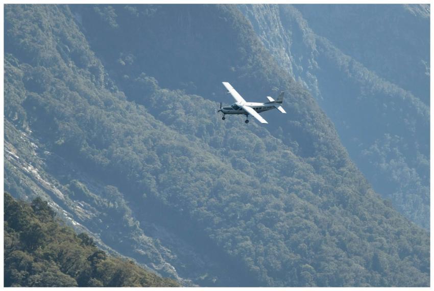An airplane soaring past lush mountain ranges, cap