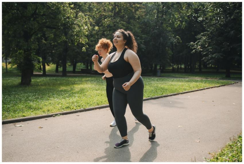 Two women jogging together in a green park, promot