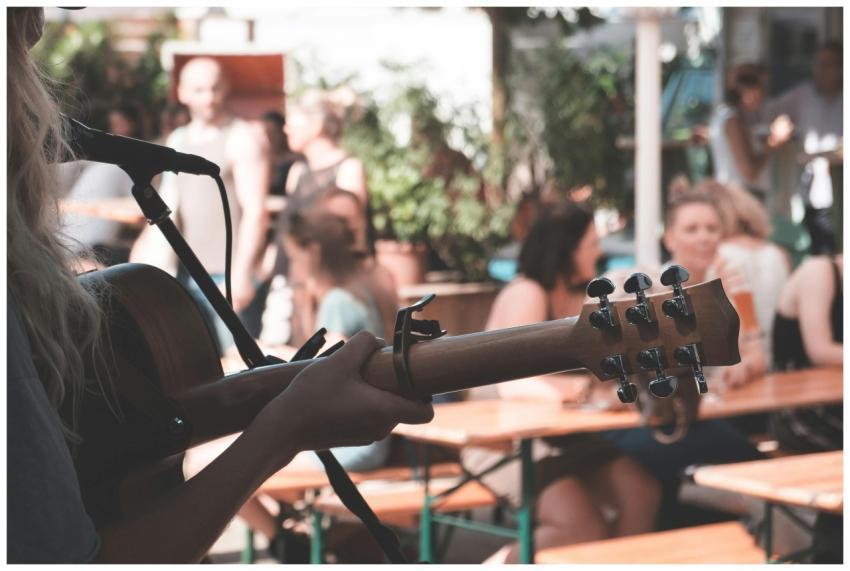 An artist plays guitar outdoors at a lively festiv
