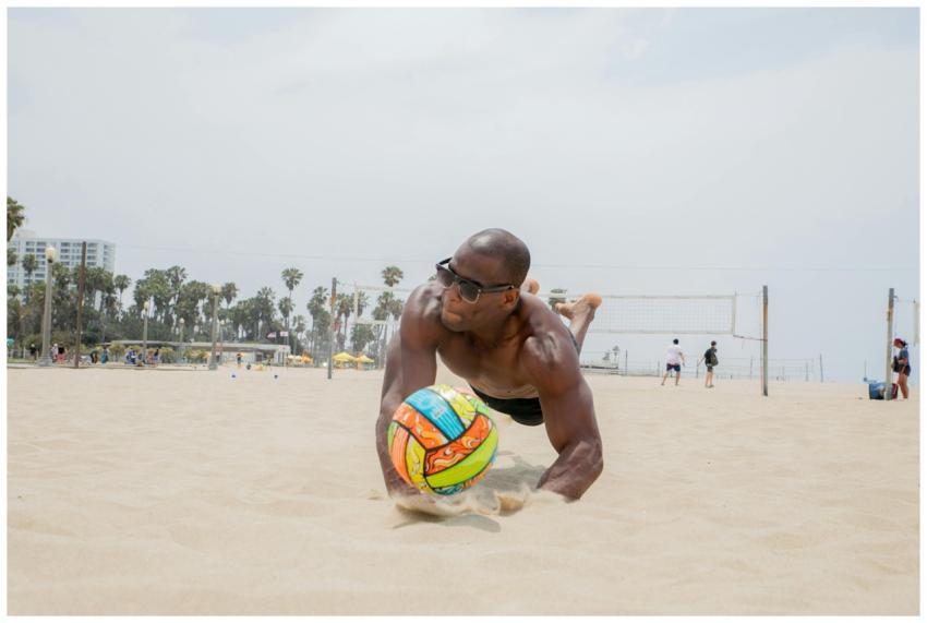 Athletic man diving for a volleyball on a sunny be